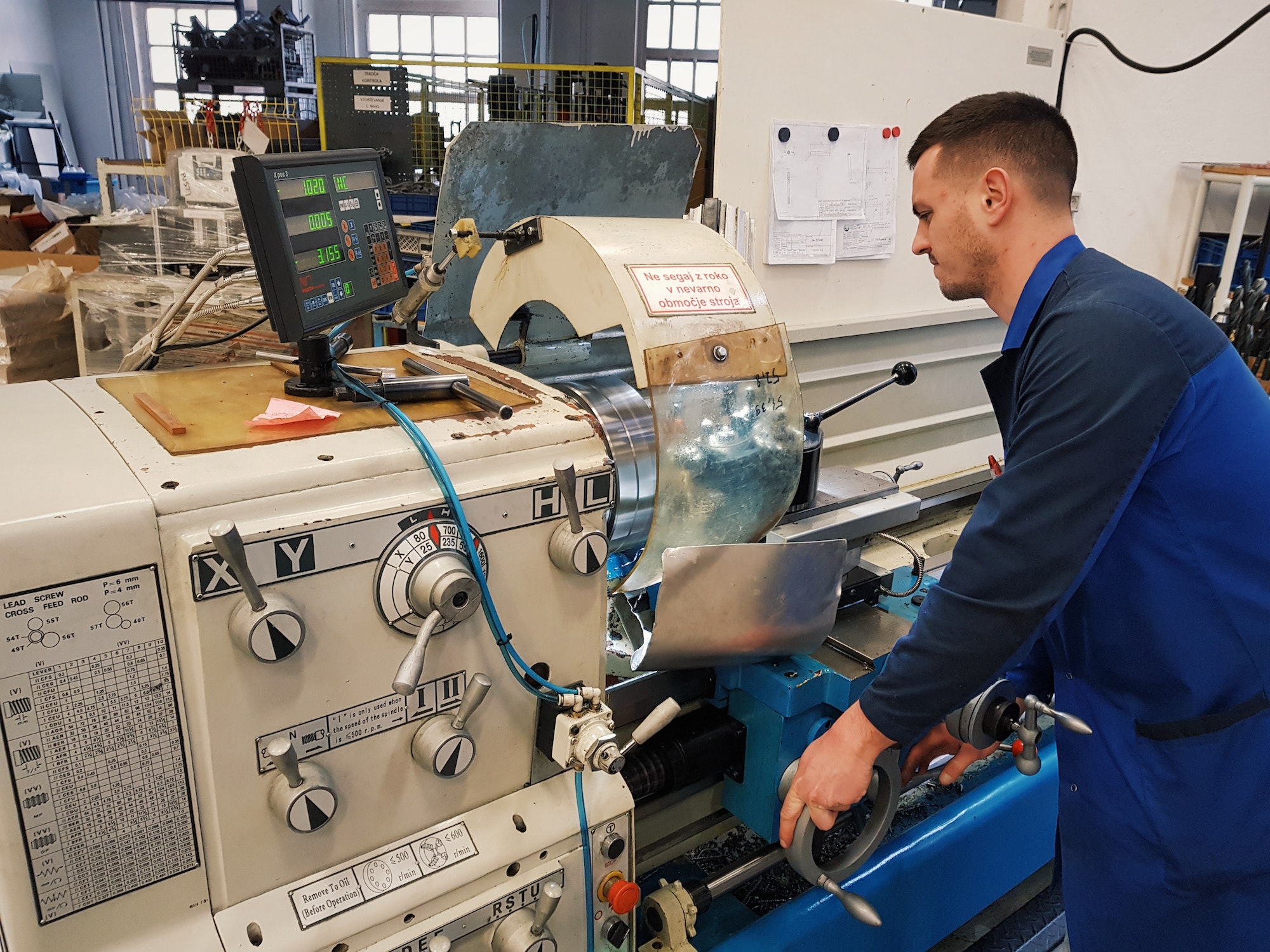 Young man working on a cnc machine in a factory.